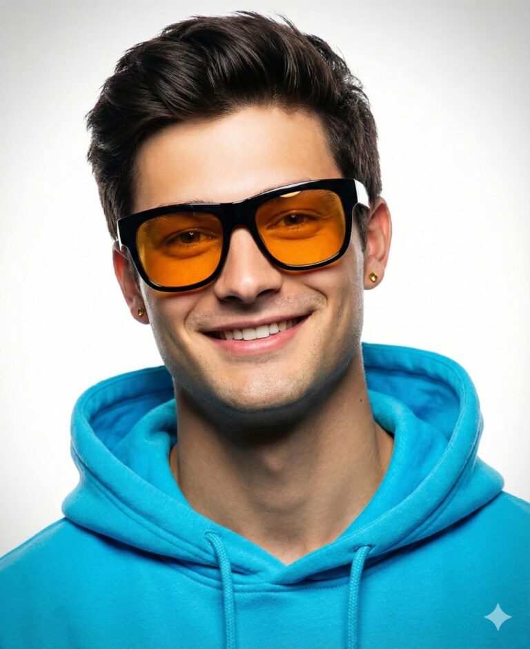 Gemini AI Generated Image: a close-up portrait of a smiling young man against a clean white background. He has dark, styled hair and is wearing a vibrant cyan-blue hoodie. His stylish look is completed by black, thick-framed sunglasses with orange-tinted lenses and small gold stud earrings, giving him a cheerful and cool appearance.